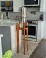 a tall hardwood stand with a stainless steel water filter on it in a light coloured kitchen setting