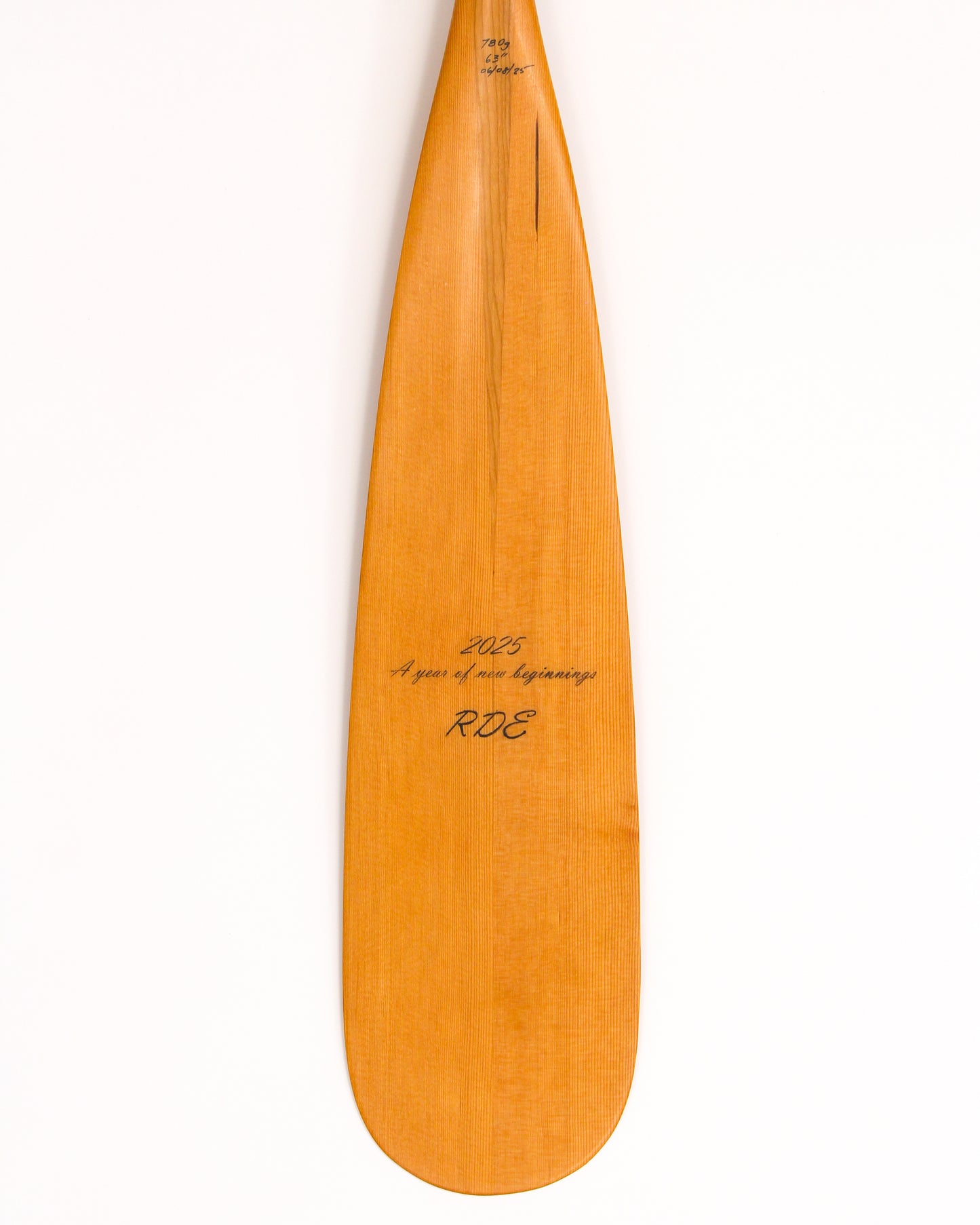 a beavertail canoe paddle that has a light colored blade and a light cherry inlay for the grip and shaft. made with BC fir and walnut and cherry hardwood. the picture shows a detail of the grip and blade