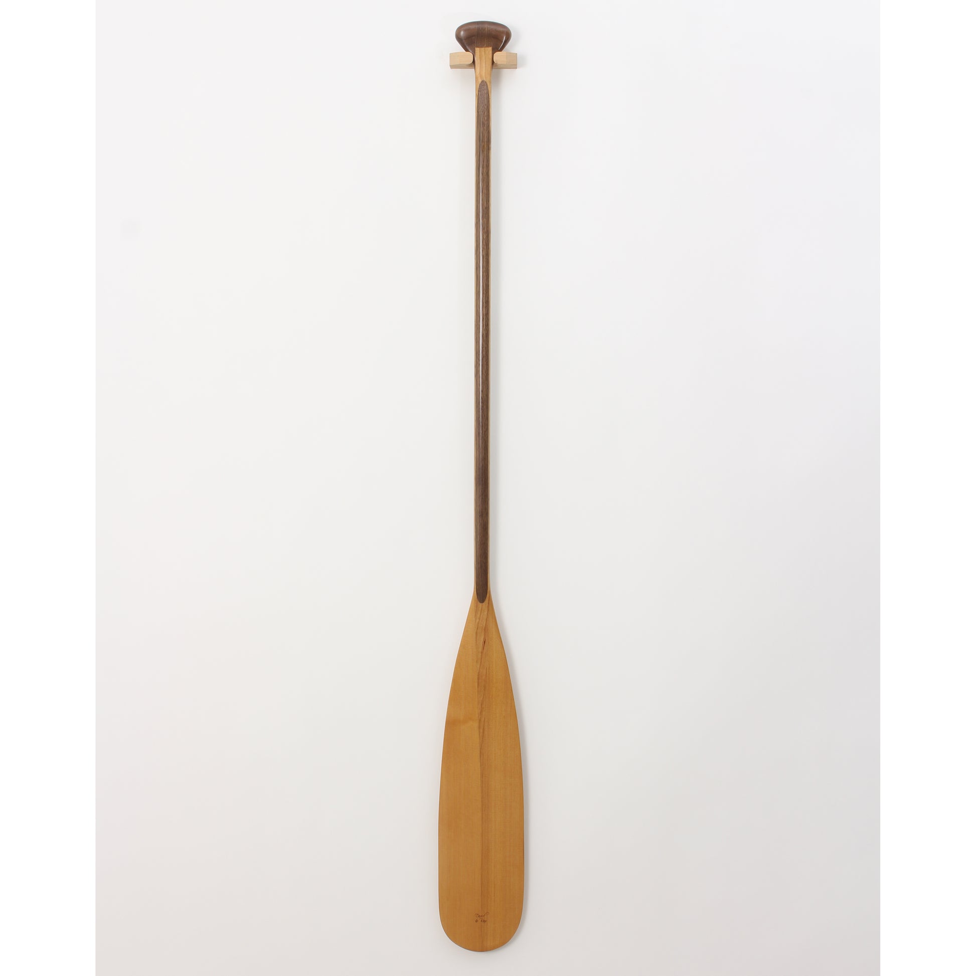 A classic beavertail canoe paddle with a laminated shaft and a pear-shaped grip, featuring a light-colored blade and a darker shaft, displayed against a white background.