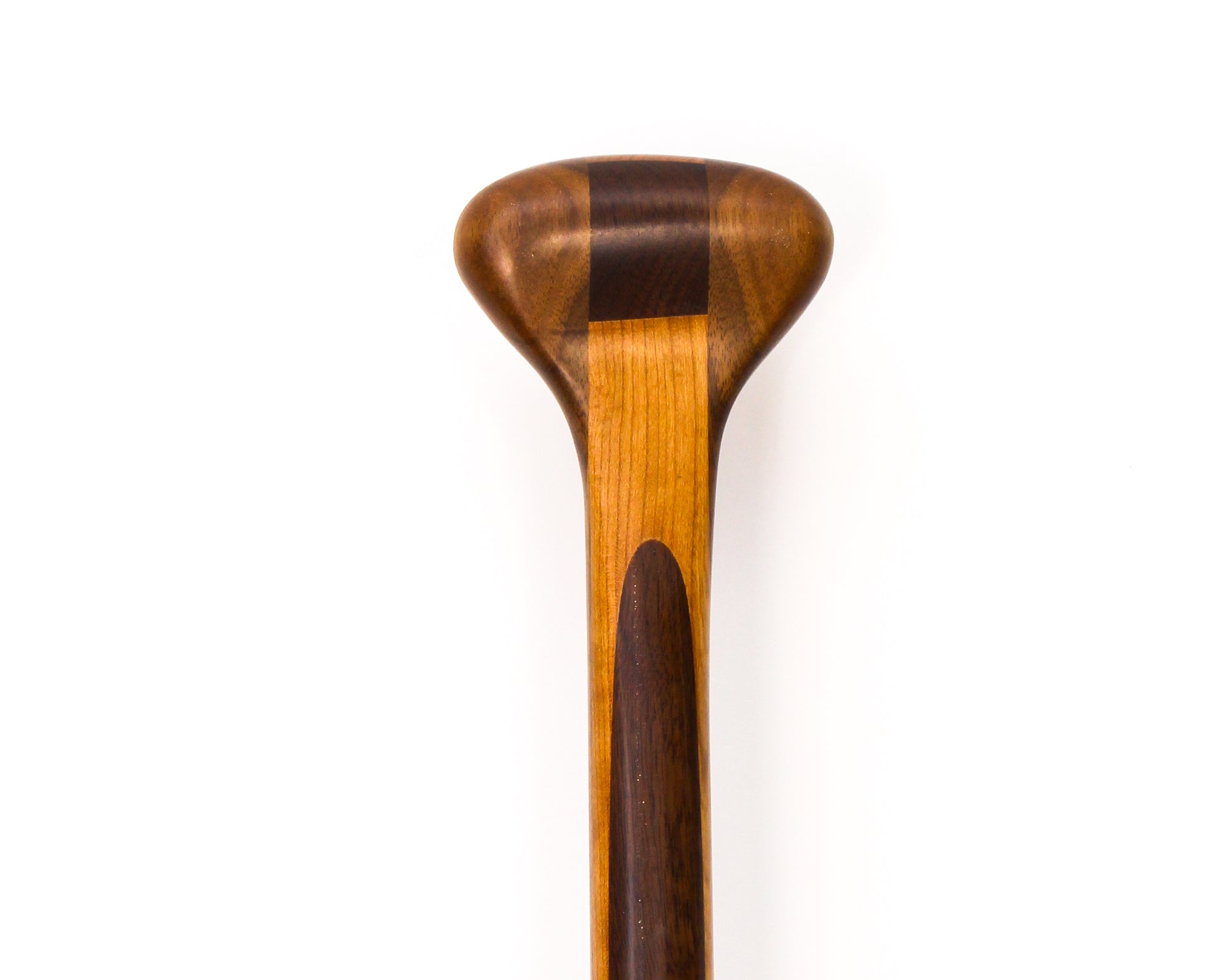 a beavertail canoe paddle that has a light colored blade and a dark inlay for the grip and shaft. made with BC fir and walnut and cherry hardwood. the picture shows a detail of the grip and blade