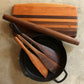 A five piece set including a cutting board made with cherry and walnut wood a walnut rolling pin and 3 walnut spatulas each with a different width and end shape
