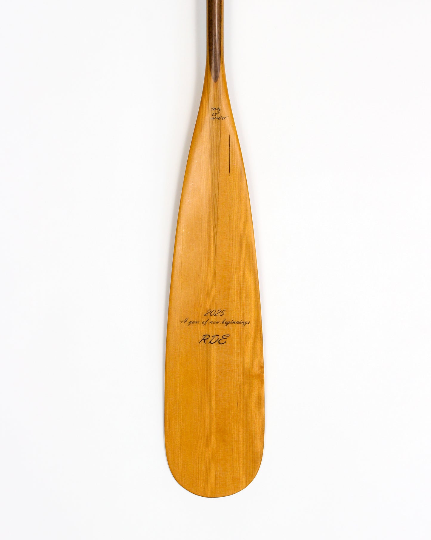 a beavertail canoe paddle that has a light colored blade and a light inlay for the grip and shaft. made with BC fir and walnut and cherry hardwood. the picture shows a detail of the grip and blade