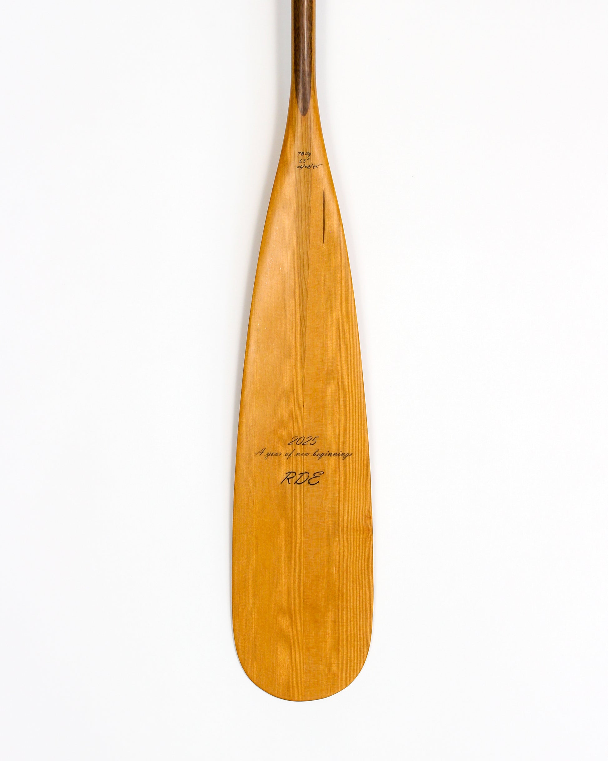 a beavertail canoe paddle that has a light colored blade and a light inlay for the grip and shaft. made with BC fir and walnut and cherry hardwood. the picture shows a detail of the grip and blade